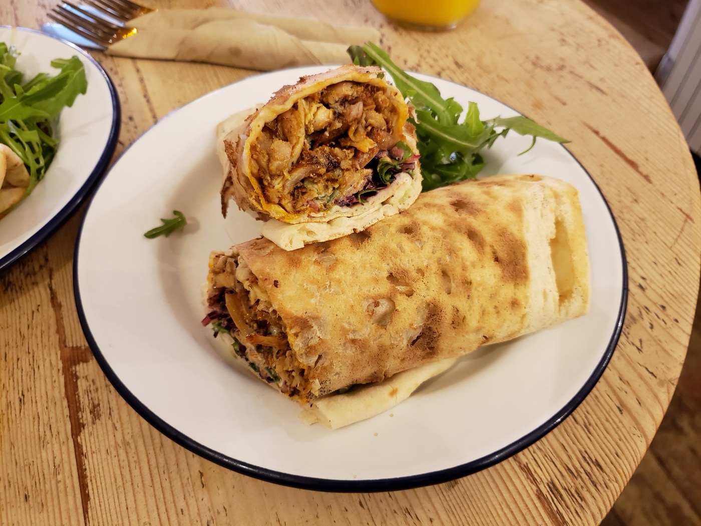 Doorgesneden wrap met gekruide kip op een wit bord op een houten tafel